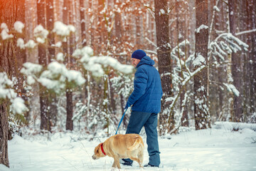 Happy man with dog walking in a winter snowy forest
