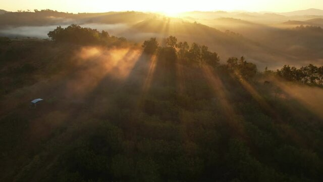Aerial view of sunrise with fog above mountains. Golden hour and amazing sun rays. Nan, Thailand 
