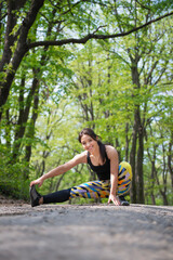 Obraz na płótnie Canvas Joyful runner stretching her legs before a spring training in the nature