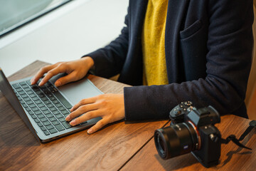 ビジネス用　女性カメラマンがパソコン作業している素材