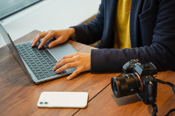 ビジネス用　女性カメラマンがパソコン作業している素材
