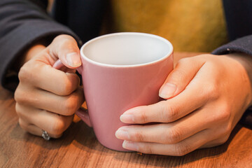 ホットコーヒーで温まる女性の手