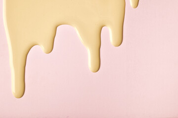 Golden liquid drops of paint color flow down on pink background. Abstract rose backdrop with beige...