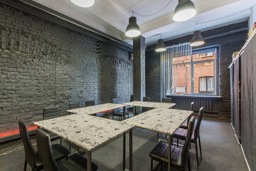 Fototapeta na wymiar Loft room with a gray brick wall for coworking. Four tables and comfortable chairs.