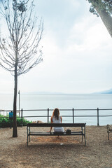 woman sitting on bench and looking at the sea