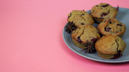 on the right, five muffins made of rice flour, yogurt, cherries and pumpkin oil lie on a gray plate on a pink background, side view. gluten-free homemade cakes