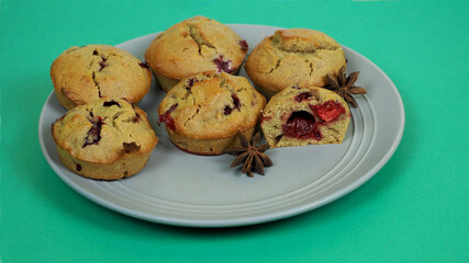 five muffins made of rice flour, yogurt, cherries and pumpkin oil lie on a gray plate on a green background, side view. gluten-free homemade cakes