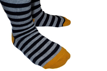 the child's feet are in striped gray-yellow socks on a white background. side view