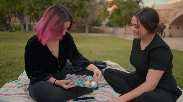 pink and brown haired girls chatting and laughing at the park. medium close up