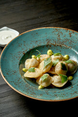 Chinese dumplings stuffed with meat with white sauce in a blue plate on a wooden background