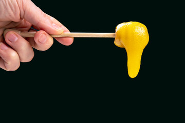 Fresh viscous flower honey falls down from a wooden spoon. vitamin organic food