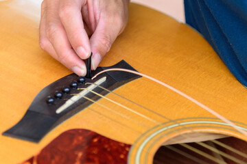 The musician replace the new guitar strings for his guitar