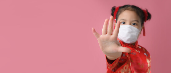 Asian little child girls in red chinese traditional dress wearing mask and  show stop hands gesture for stop corona virus .Happy Chinese new year concept.