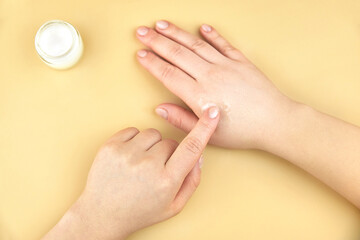 Obraz na płótnie Canvas A woman moisturizes her hands with a protective cream.