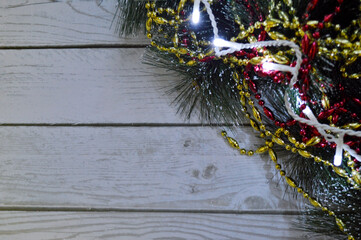 Christmas background of light wood with fir branches, garland,gold and red beads