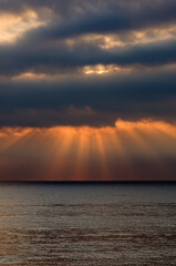 The rays of the sun are breaking through the thick clouds. Nature in twilight. Tropical sea sunrise. Sky background