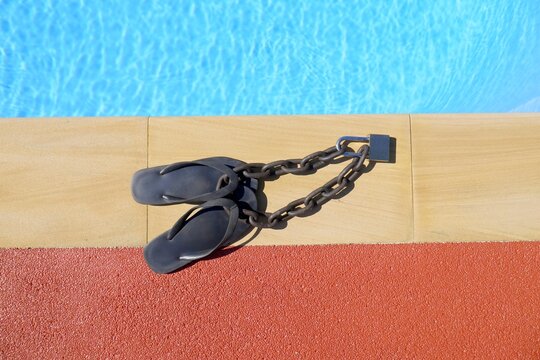 Pair of flip flops padlocked to a steel chain, protection of your belongings, insurance against theft