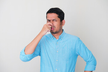 Adult Asian man closed his nose with hand when smell something bad