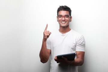 Smiling young man of Indian origin holding a tablet computer