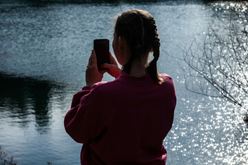 A tourist takes pictures of the lake on his phone during the day