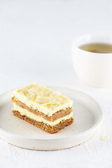 A piece of lemon cake with almonds in a plate with a cup of tea. Sugar, gluten and lactose free and vegan.