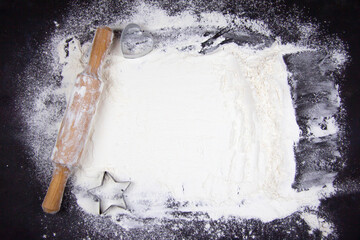 Abstract baking background with copy space on a black surface for text. Spot on black, top view on the board. The concept of baking, the preparation of dough or dough.