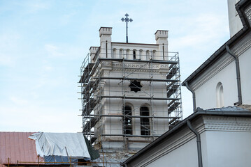 The tower of an old monastery under renovation. Scaffolding mounted on the building to repair the walls.