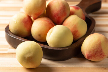 Peaches, beautiful peaches on a dark wooden tray positioned on a rustic wooden surface, selective focus.