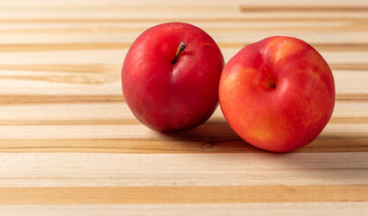 Plums, beautiful and juicy plums positioned on a rustic wooden surface, selective focus.