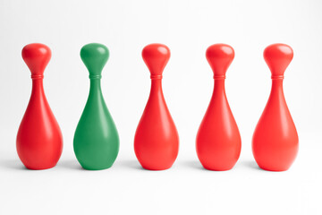 Four red and one green skittle in a row on white background. Teamwork with outstanding team member or leader. Dare to be different. Standing out from the crowd. Ash conformity study.