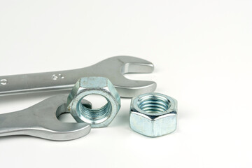A small group of silver fasteners to secure the structure. Nuts close-up on a white background. Several wrenches.
