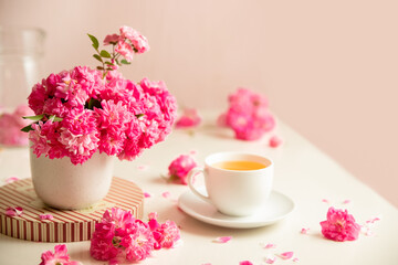 roses and tea cup served for breakfast on plain background, copy space for text, valentine's day, wedding or anniversary morning decorations. 