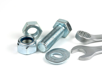 A small group of silver fasteners for fastening structures. Bolts and nuts with washers close-up on a white background. Several wrenches.