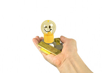 Light bulb or lamp toy yellow emoticons smile,gold and silver coins on hand isolated on white background.Concept Business idea to make money.