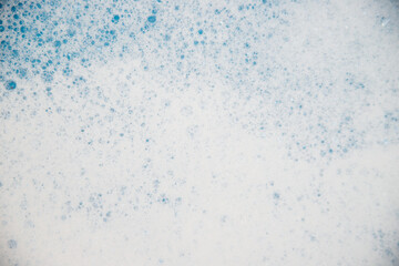 Abstract background texture of white soap foam. Shampoo foam with bubbles on a blue background.
