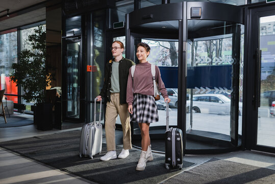 Young couple with suitcases walking in hotel lobby