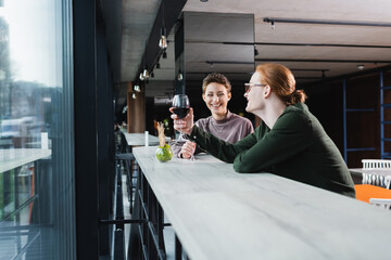 Obraz premium Smiling couple holding glasses of wine and talking in hotel