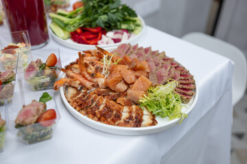 Seafood on a plate. Buffet. Shrimp, eel, salmon. White tablecloth on the table.