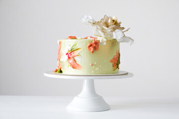 White wedding cake decorated with golden flowers on a white background.