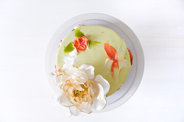 White wedding cake decorated with golden flowers on a white background. Top view.