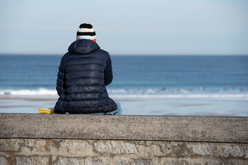 man sitting looking at the sea in winter