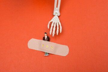Hand of a model skeleton beside medical plaster on model man figurine