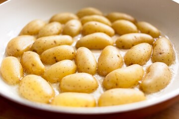 cooking fried potatoes in white pan