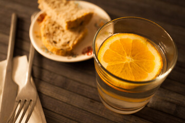 a glass of orange juice with lemon and bread