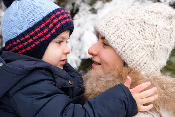 Mother and son look at each other in the winter forest, family pastime, vacations