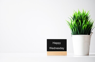 Happy Wednesday words on table and green plants in pots