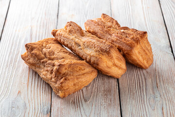 Freshly baked tasty bun on a white wooden table. Tasty baked goods straight from the bakery. White background.