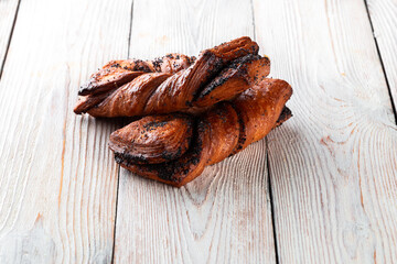 Freshly baked tasty bun on a white wooden table. Tasty baked goods straight from the bakery. White...