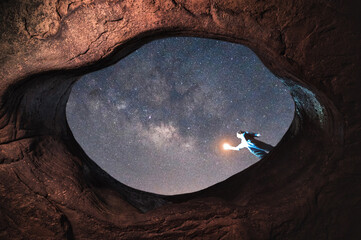 Woman holding lamp standing on top of big hole with milky way in the night sky