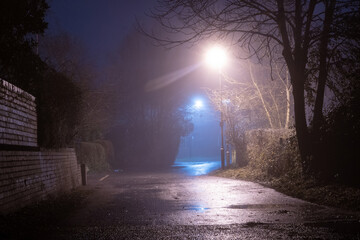 A spooky empty country road, with street lights. On an atmospheric foggy winters night. UK